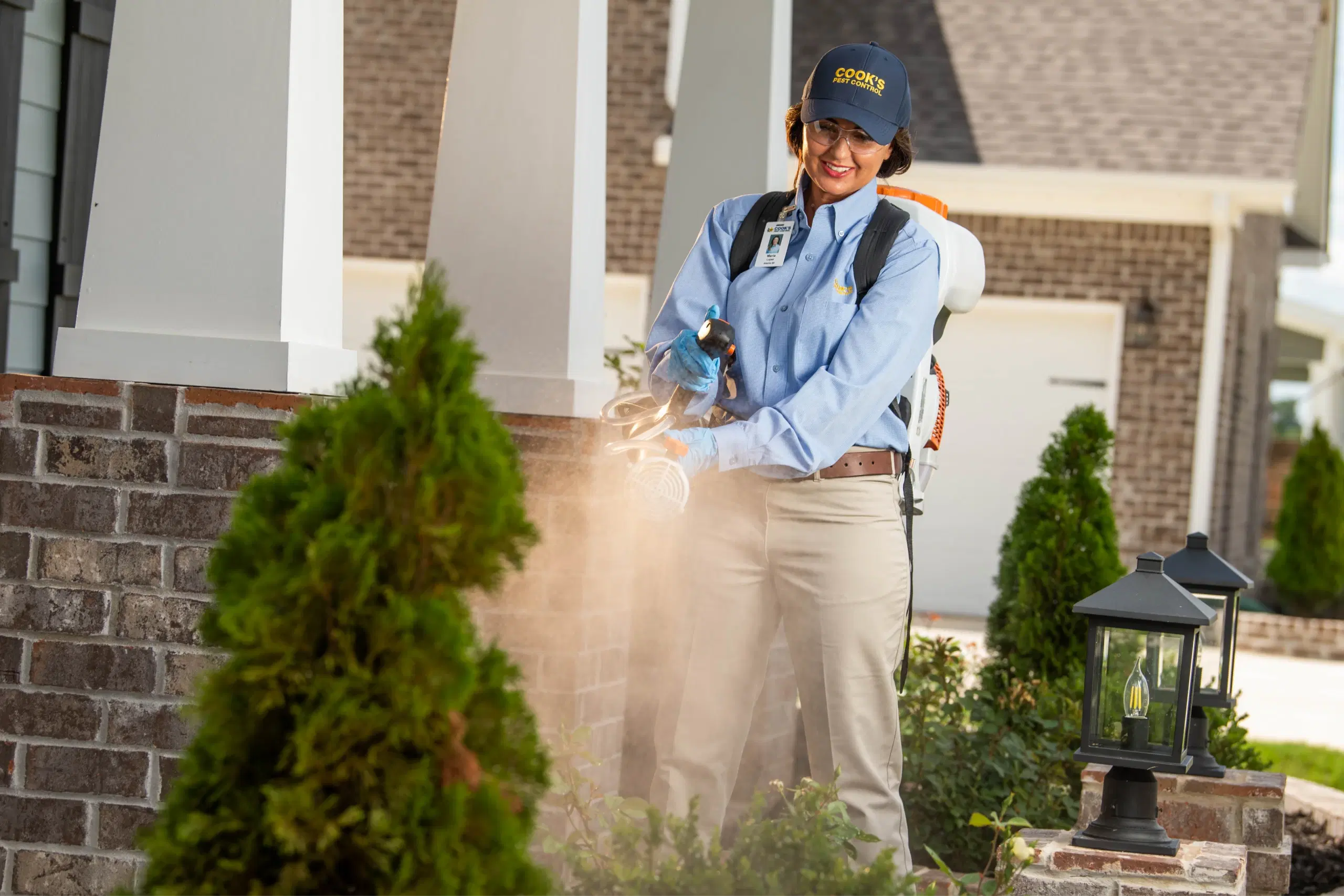 Cook's technician spraying for mosquitos around a house.